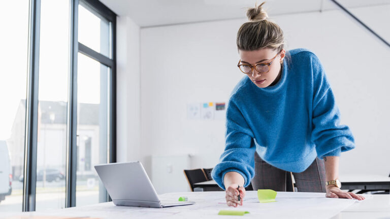 Woman with glasses standing and filling out paperwork.