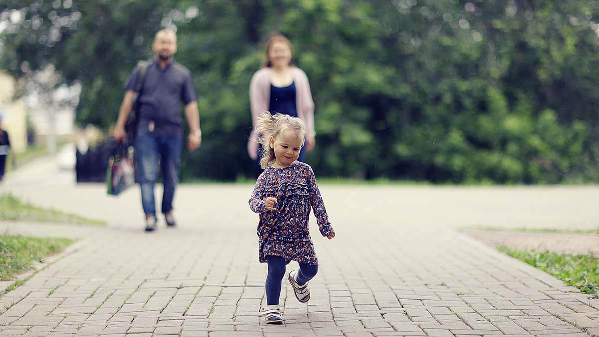 Toddler running in front of parents.