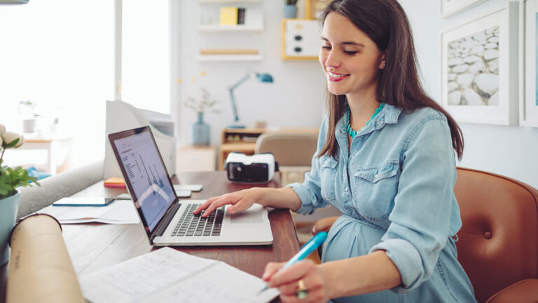 Woman using a laptop with financial statements on the screen.