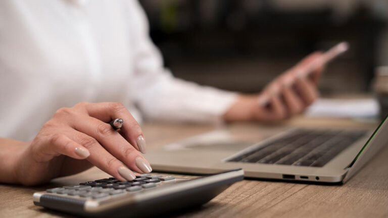 Business owner calculating backup withholding on calculator.
