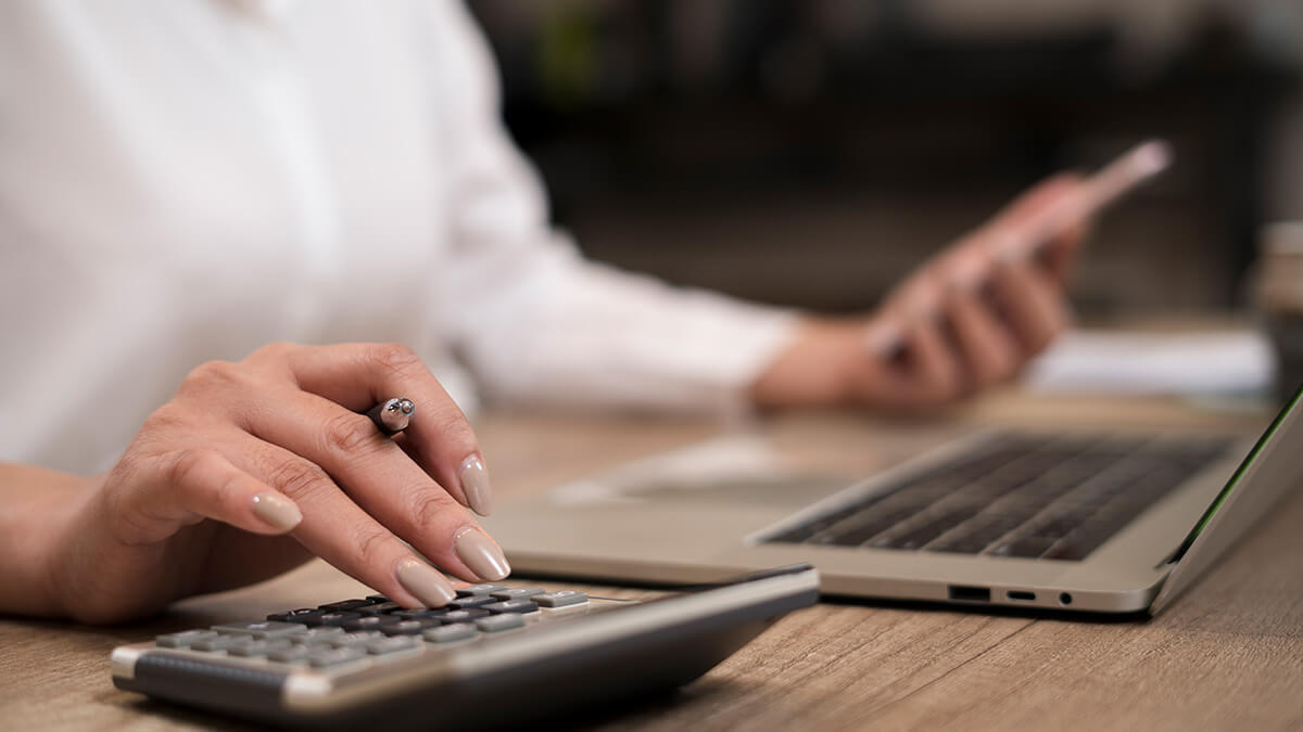 Business owner calculating backup withholding on calculator.