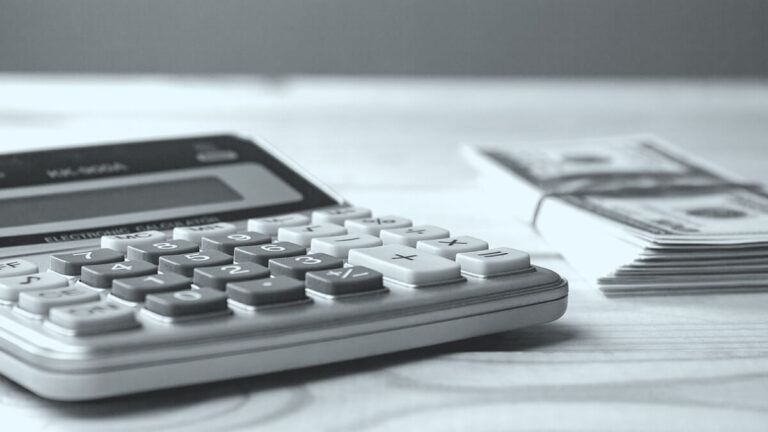 Calculator and stack of bills on a table.