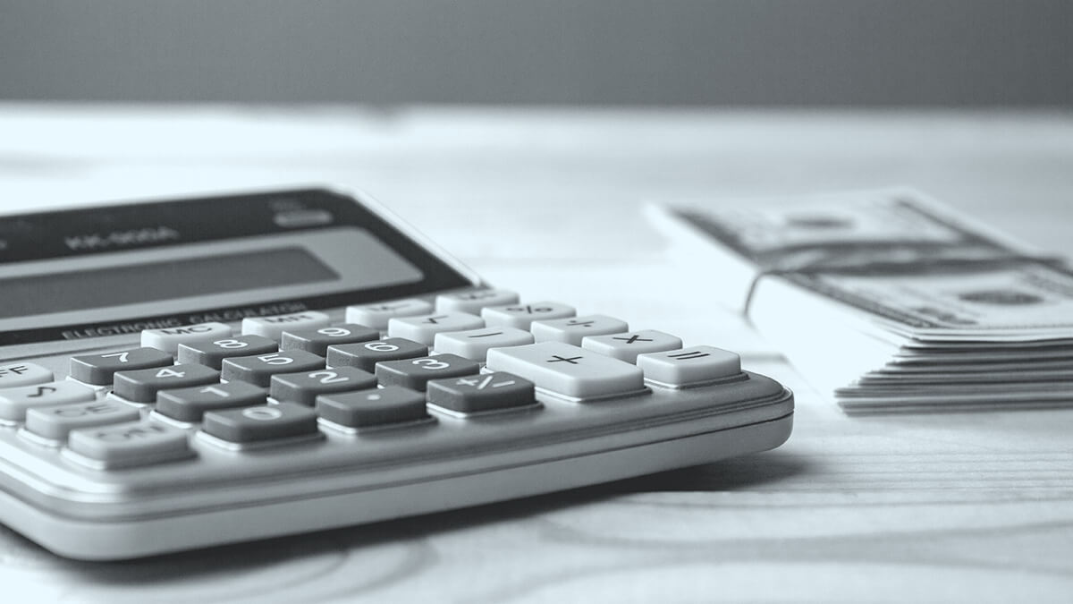 Calculator and stack of bills on a table.