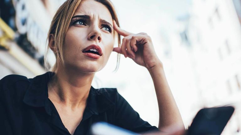 Confused woman with hand to forehead.