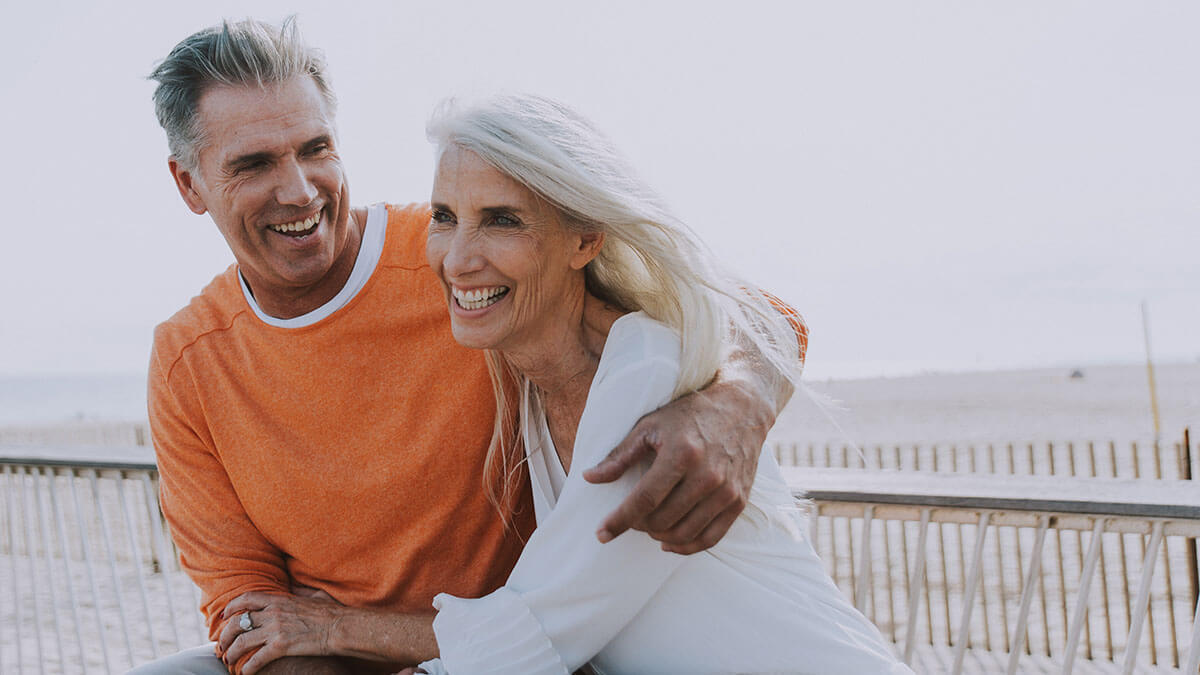 Retired couple embracing on the beach.