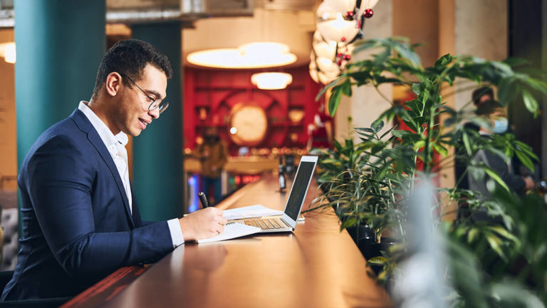 Man working at a tall counter with plants around him.