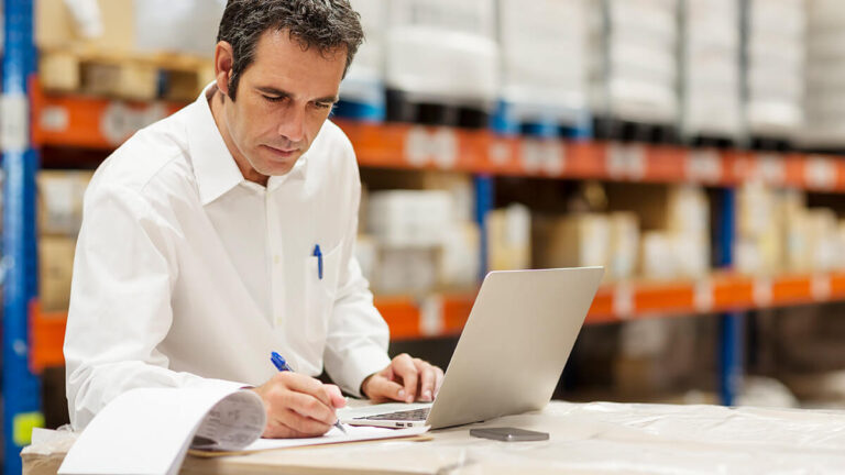 Man using a laptop in a warehouse.