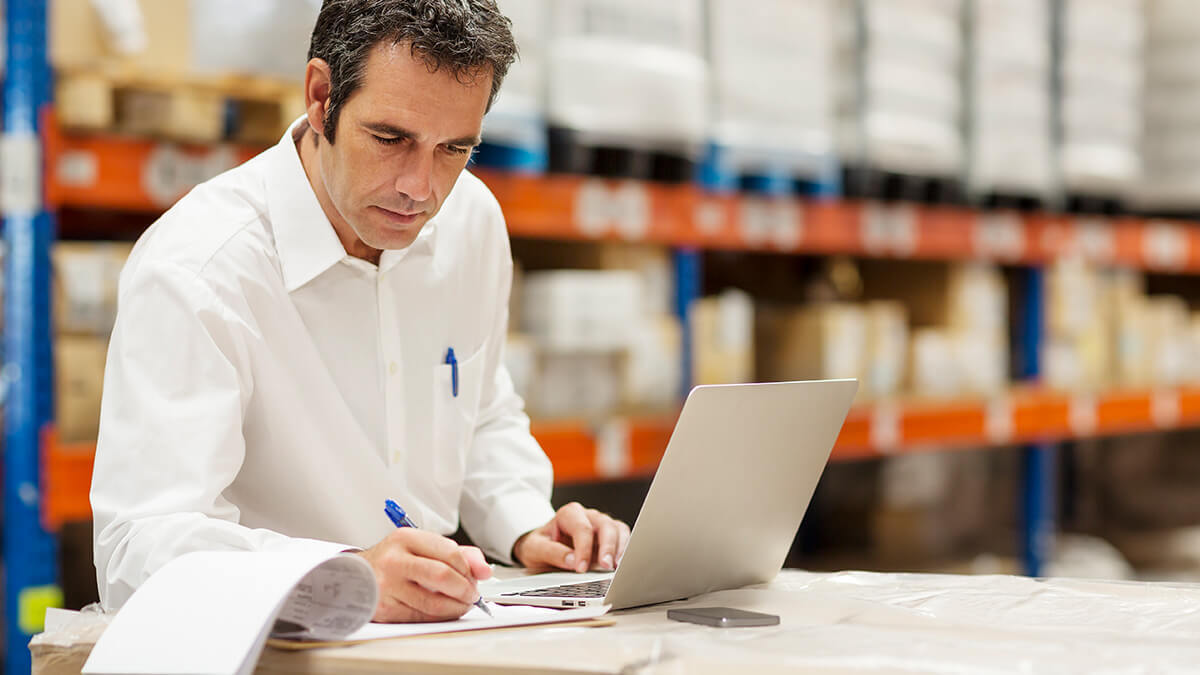 Man using a laptop in a warehouse.