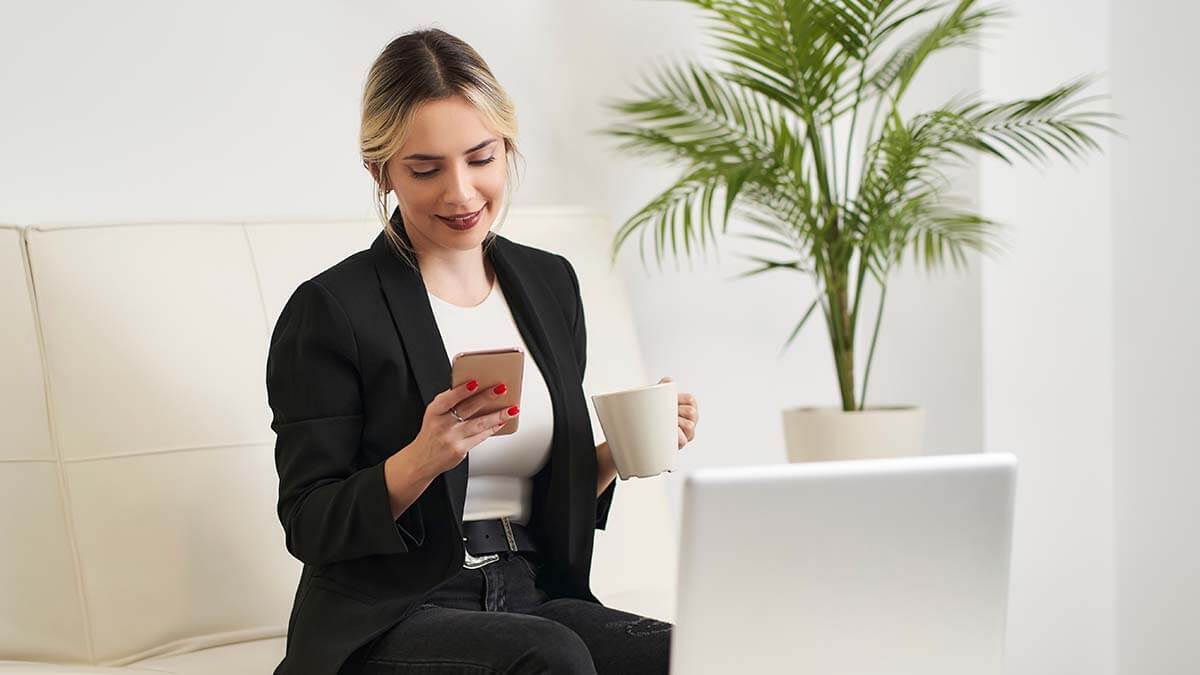 Woman holding a mug and researching how much it costs to start a business.