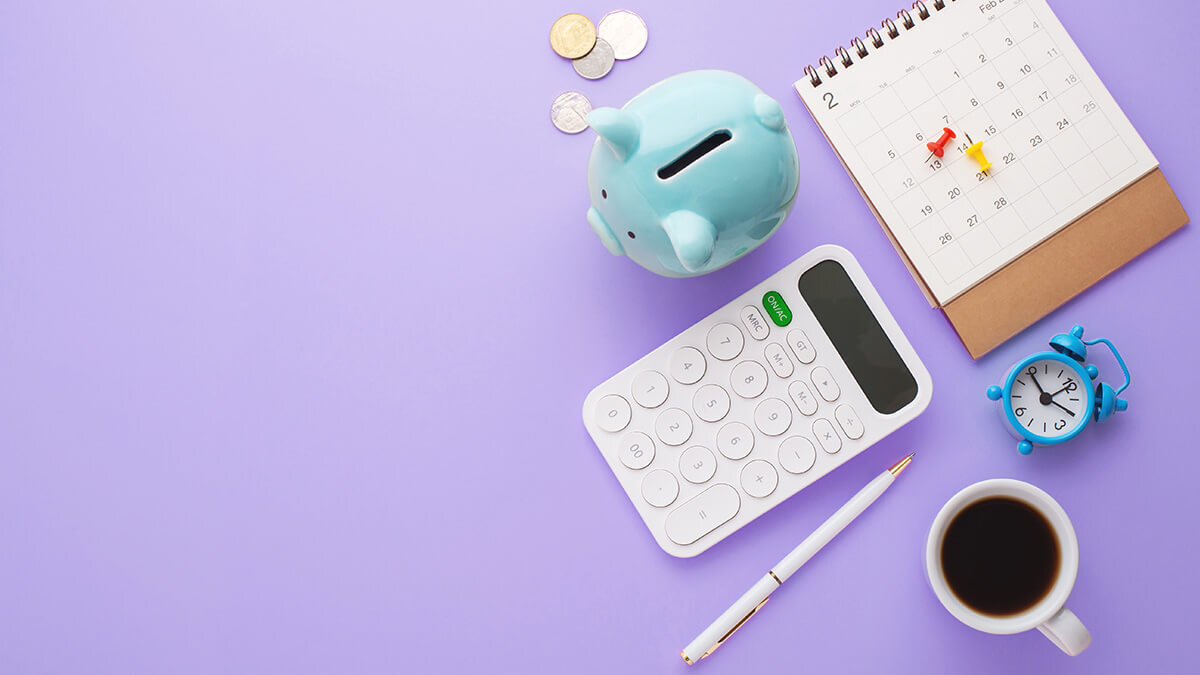 Assorted objects including coffee, a piggy bank, and a calculator on purple background.