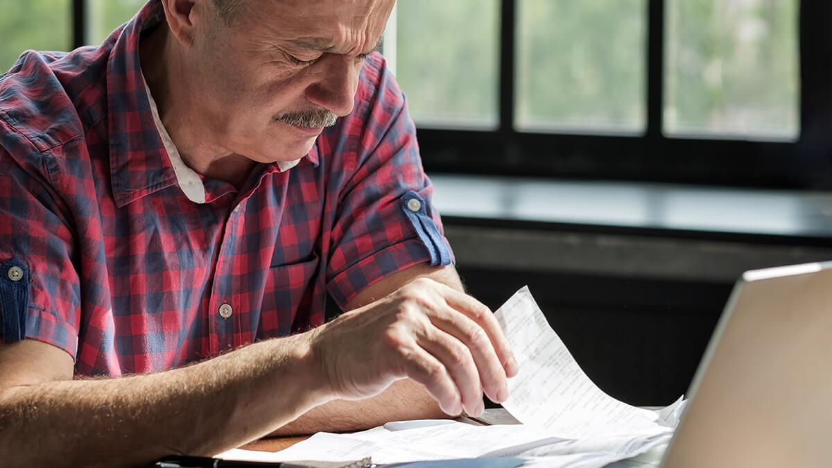 Older gentleman with a mustache looking at receipts.
