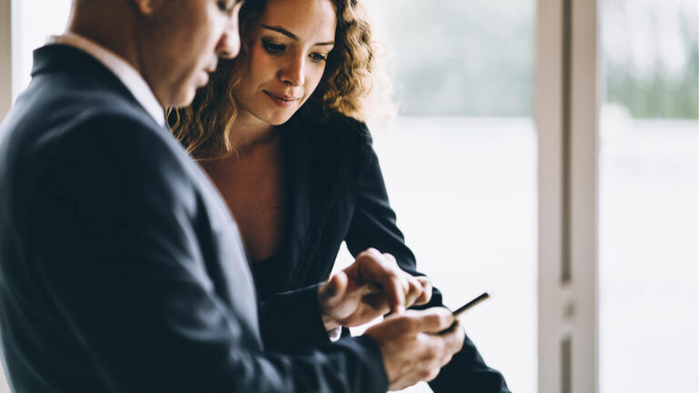 Two colleagues look at a cell phone.