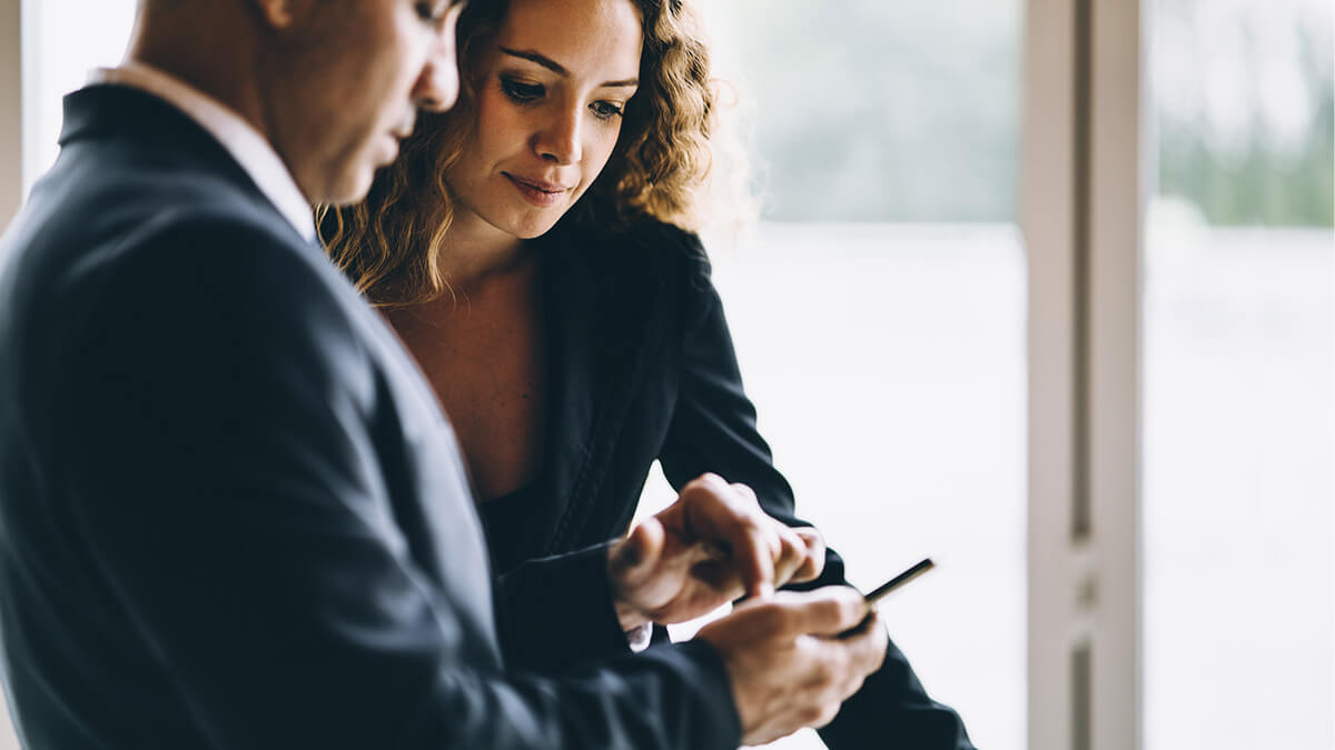 Two colleagues look at a cell phone.