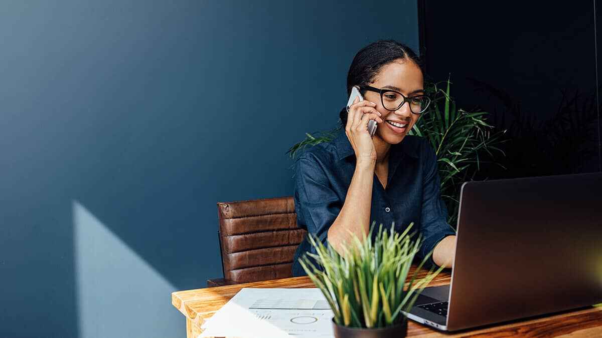 Woman on the phone while using a computer.