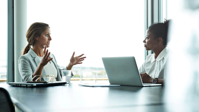 Two women discussing a salary reduction.