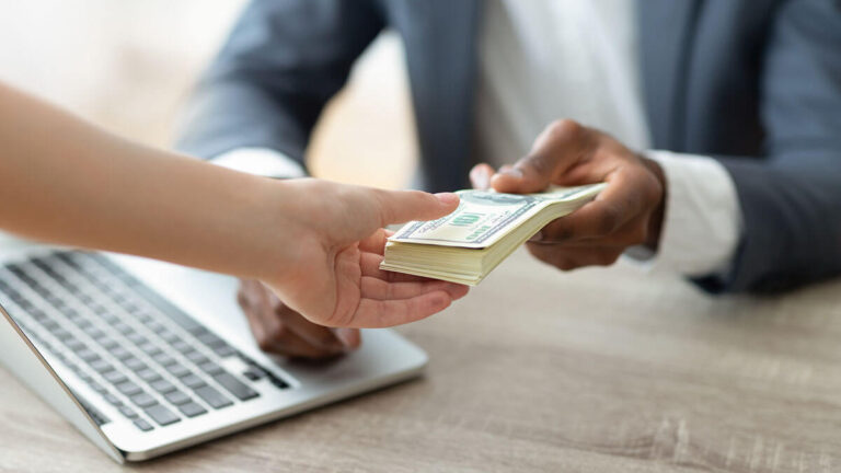 Business owner putting a stack of money in someone's hand.