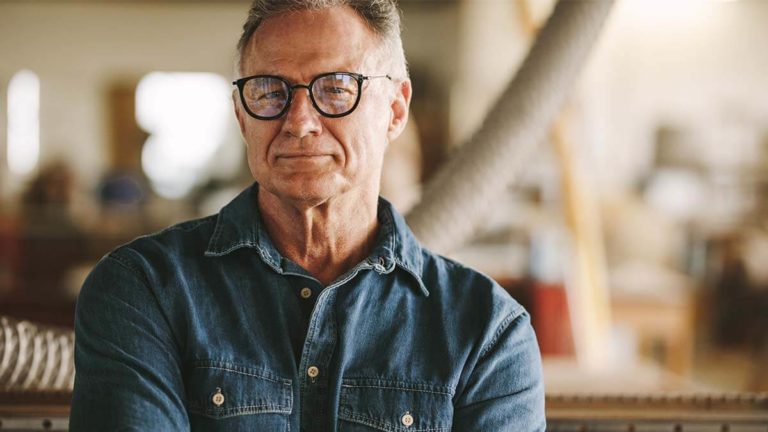Older man with glasses looking seriously at the camera.