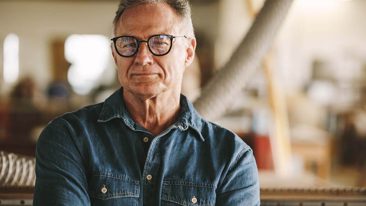 Older man with glasses looking seriously at the camera.