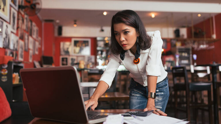 Business owner checking historical cost data on laptop.
