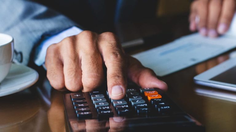 Man calculating payroll taxes with calculator.