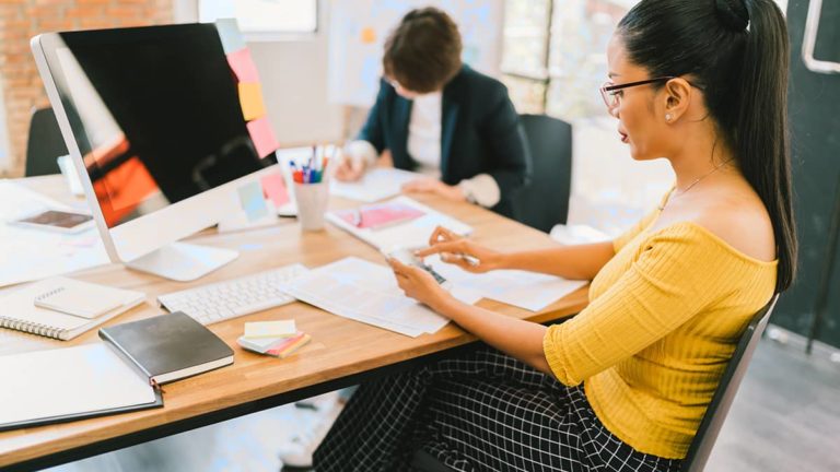 Side profile of employee using a small calculator.