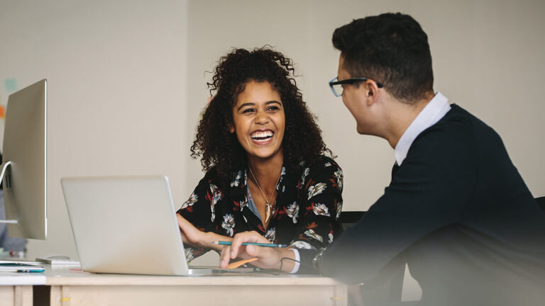 Woman smiling at male co-worker.