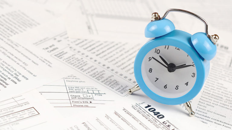 Blue alarm clock on paperwork.