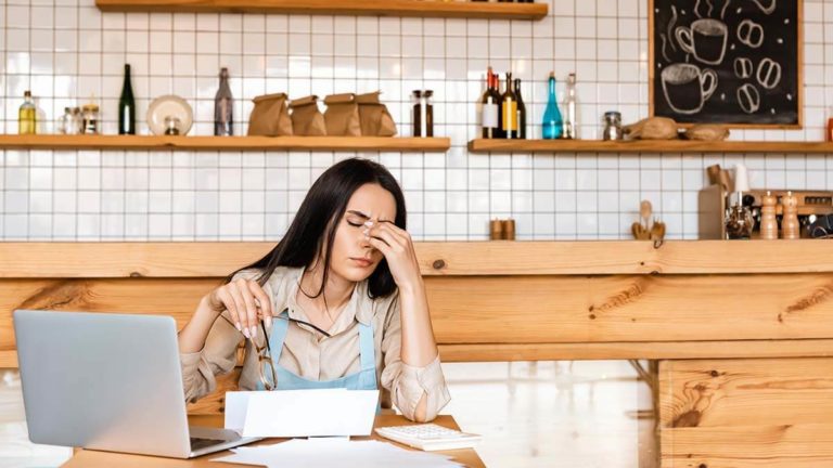 Stressed business owner rubbing bridge of nose.