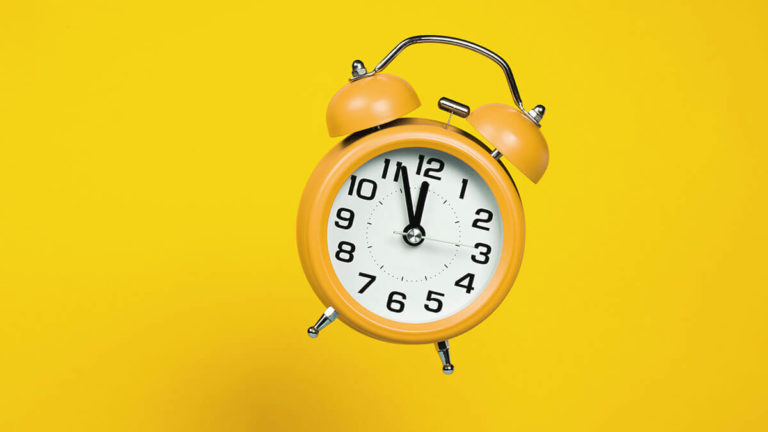 Yellow alarm clock on a yellow background.
