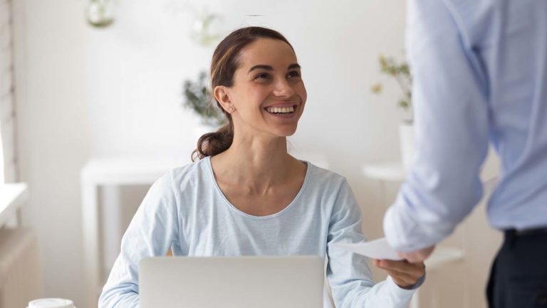 Woman smiling as man hands her paperwork.