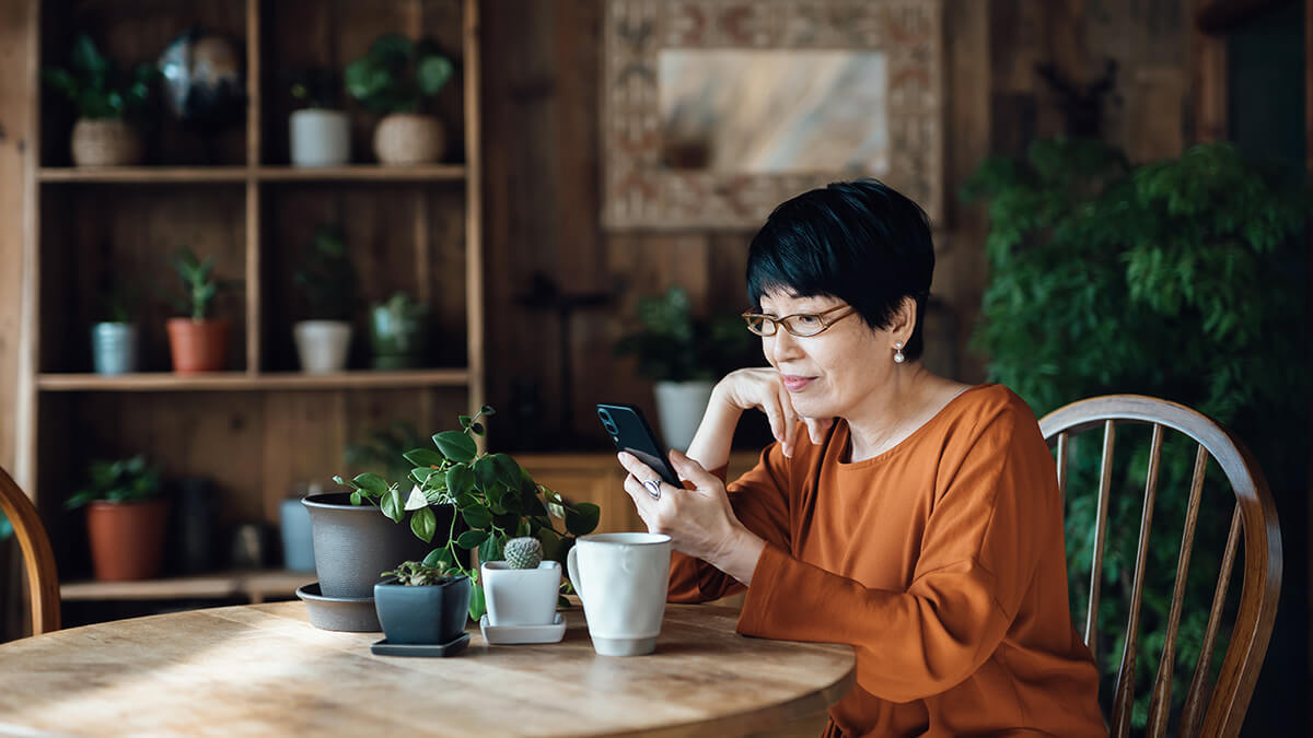 Woman at dining room table looking at cell phone.