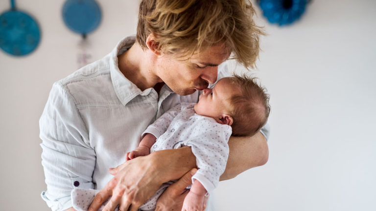 Dad kissing newborn baby.