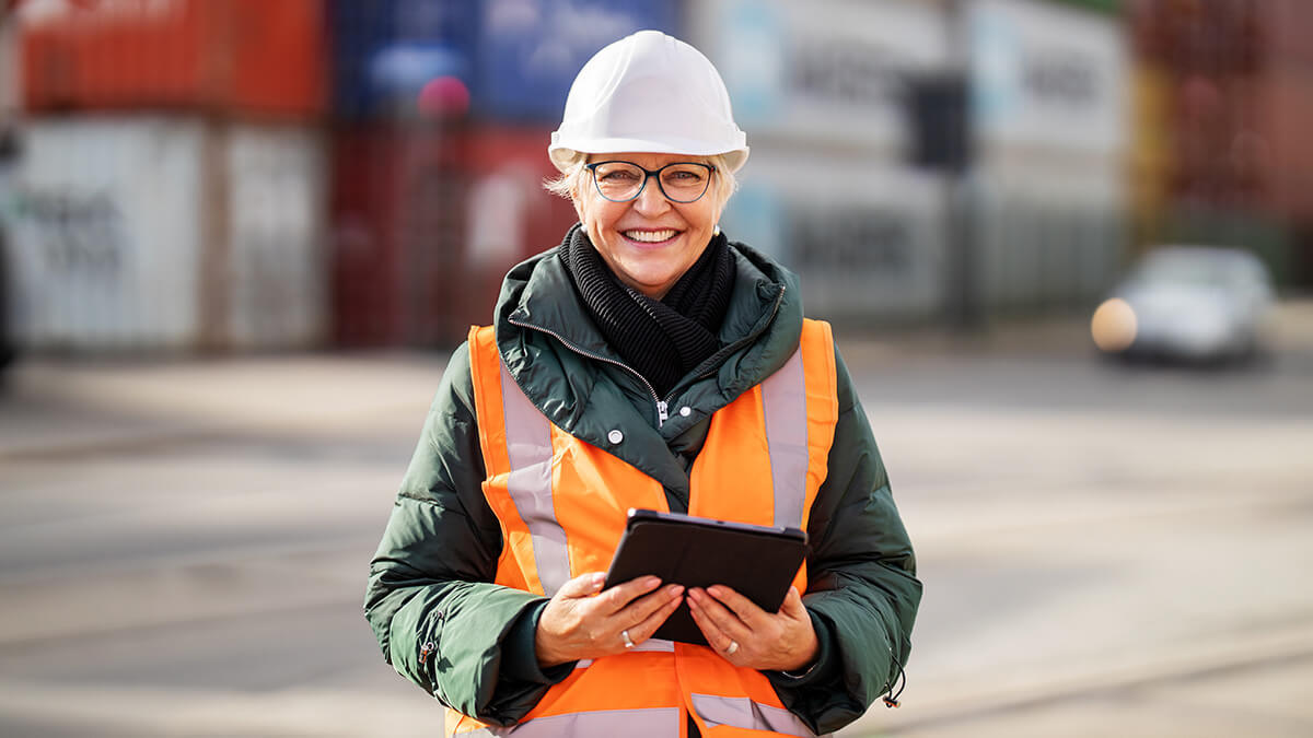 Smiling female construction worker in an orange vest.