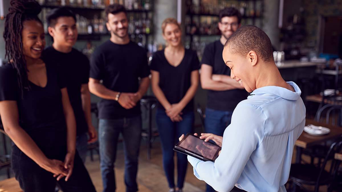 Manager talking with team of tipped employees.