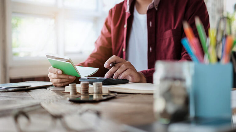 Business owner using a calculator and holding a notepad.