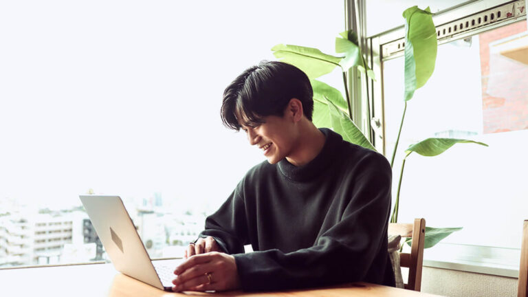 Man smiling at his laptop.