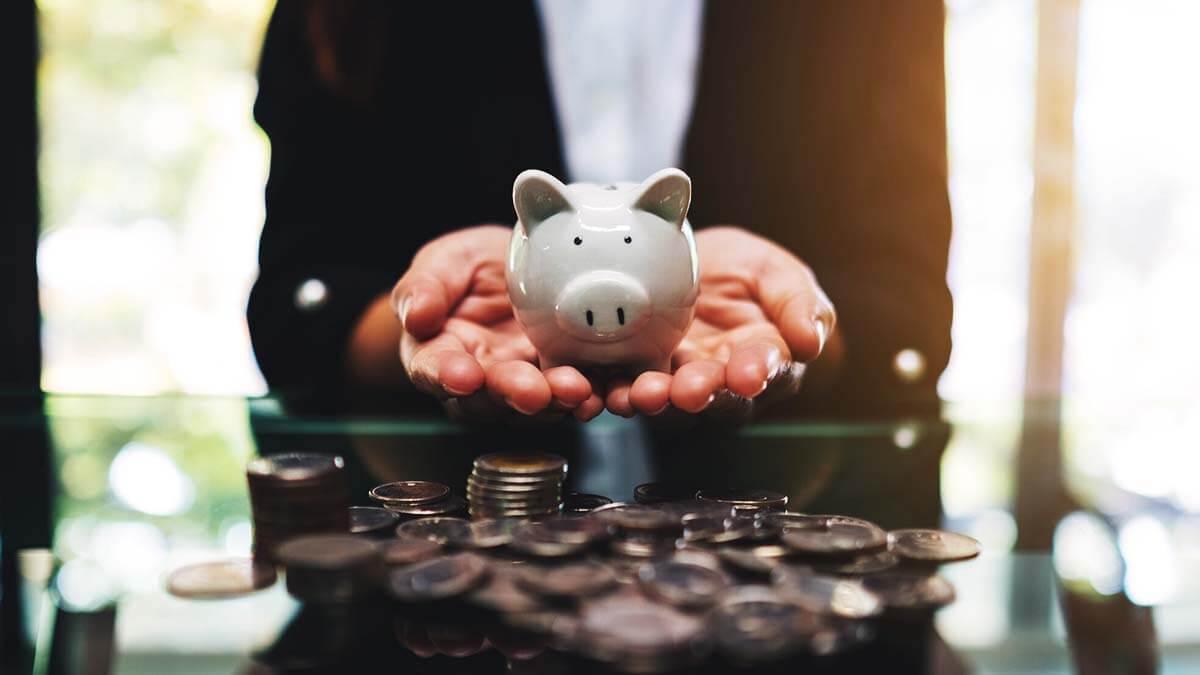 Woman holding a piggy bank; coins on the table.