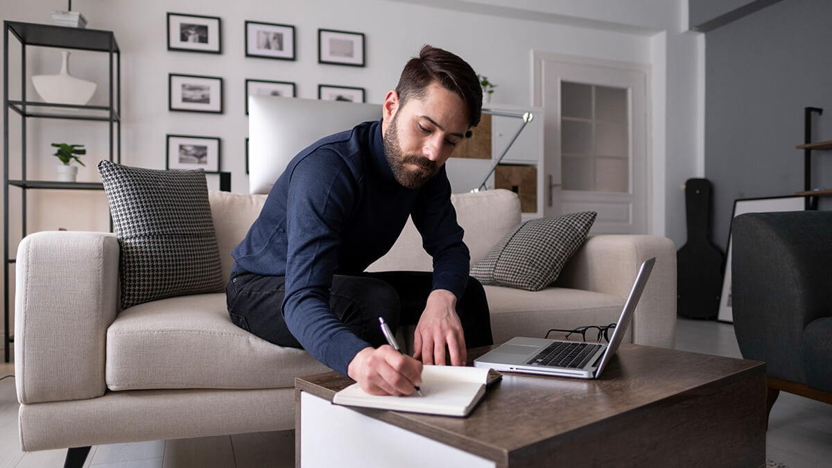 Man sitting on the couch jotting down payroll history.