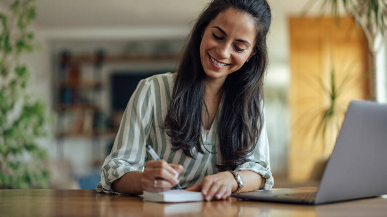 Smiling woman writing on a notepad.