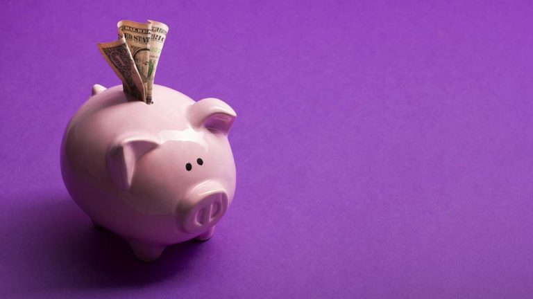 Pink piggy bank with a bill sticking out.