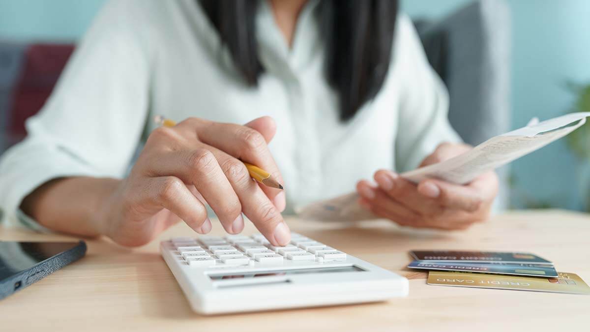 Woman calculating pre-tax and post-tax deductions on calculator.