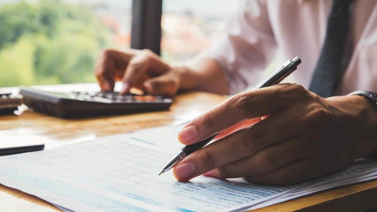 Business owner using calculator and writing.