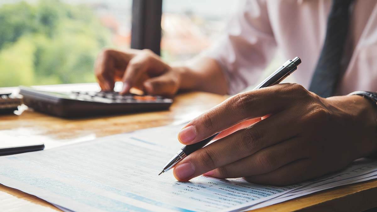 Business owner using calculator and writing.