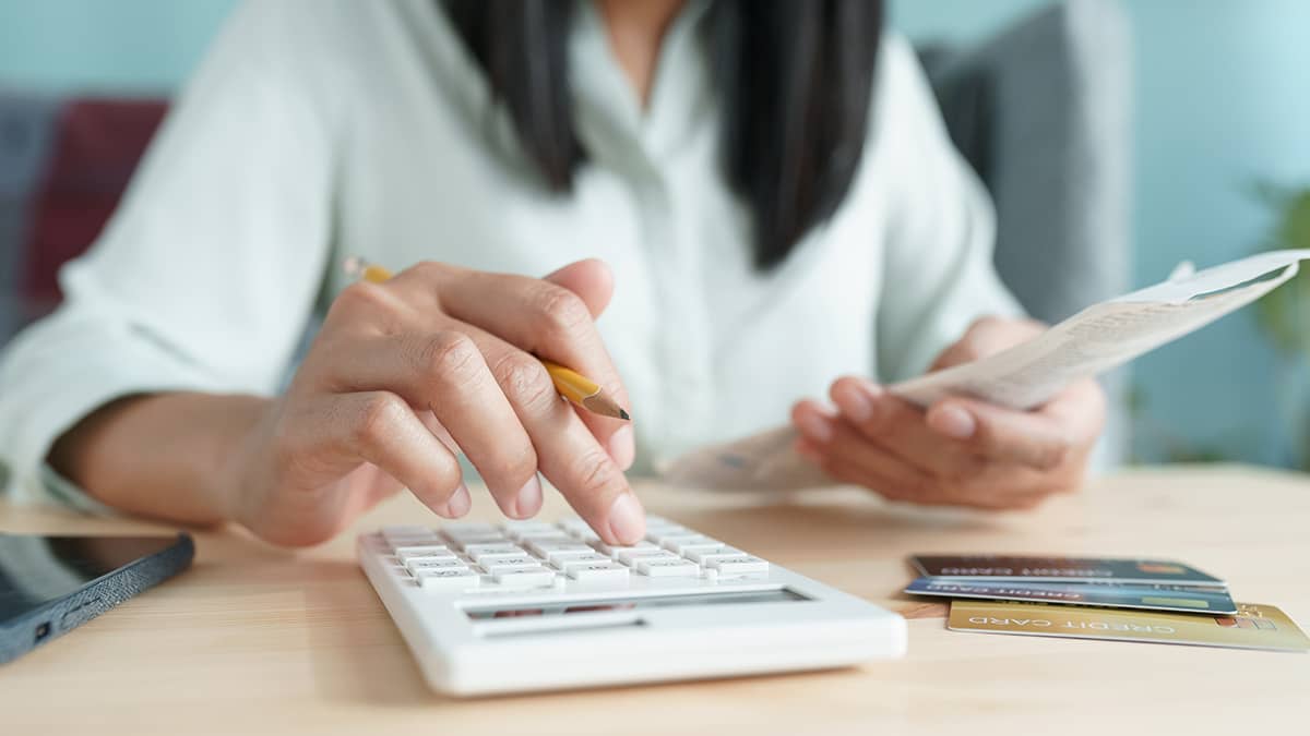 Business owner calculating purchase returns on calculator.