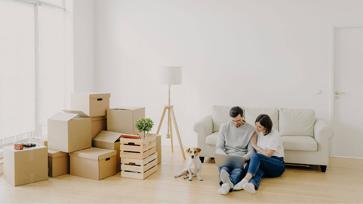 Recently relocated couple and dog surrounded by boxes.
