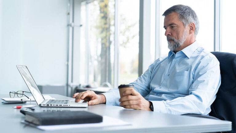 Older man working on a laptop.