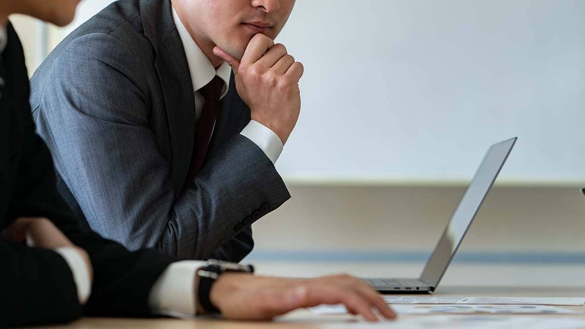 Man in a suit with his hand to chin.