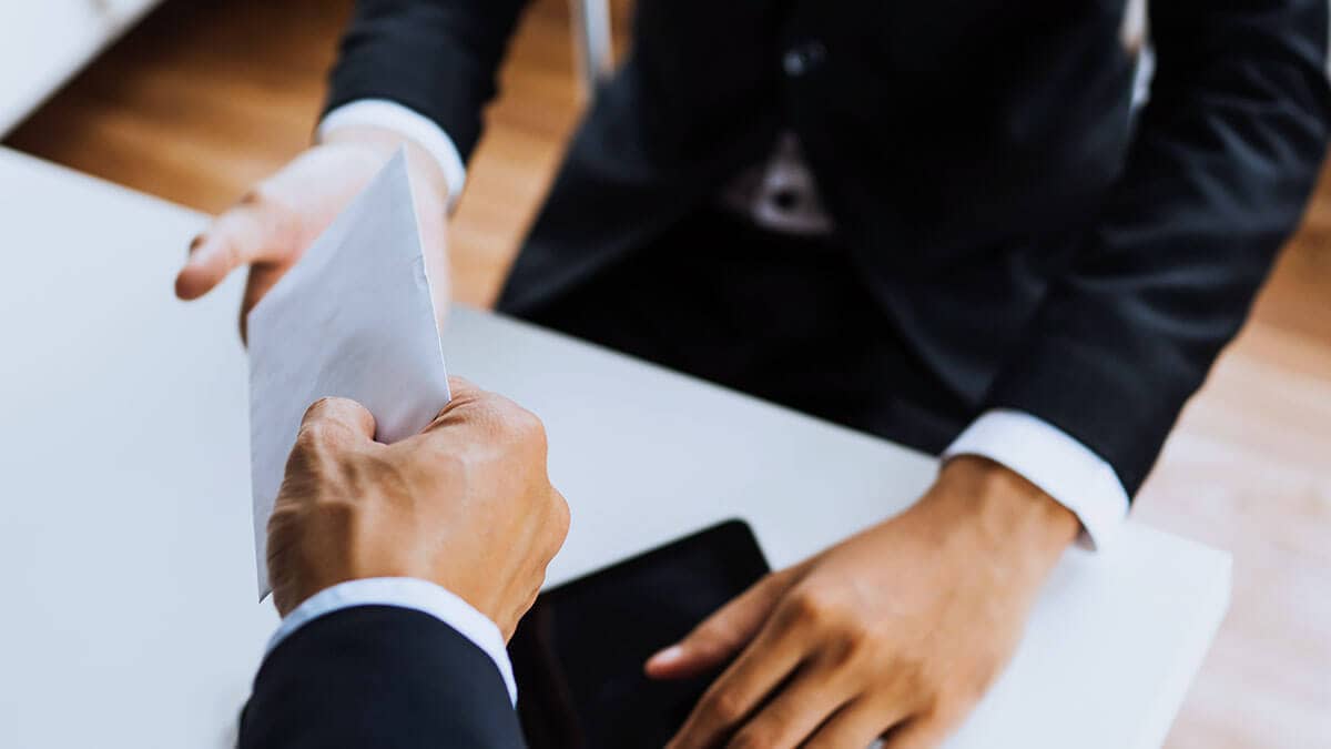 Hand giving an envelope to someone.