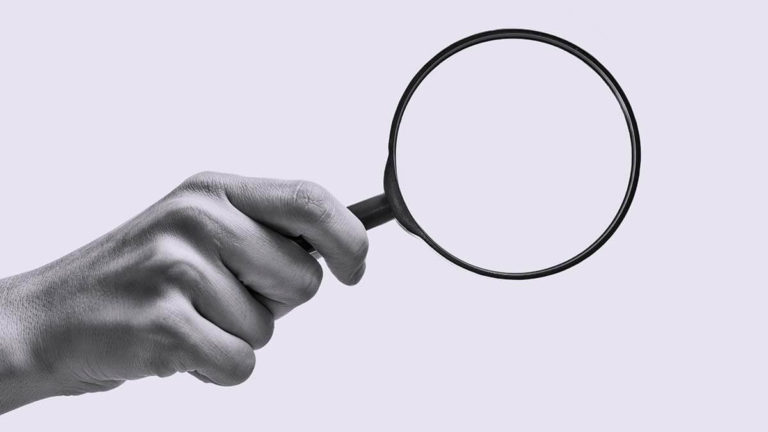Hand holding a magnifying glass.