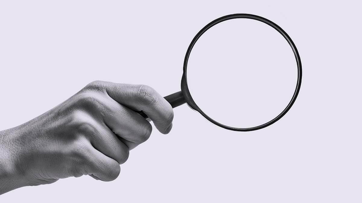 Hand holding a magnifying glass.